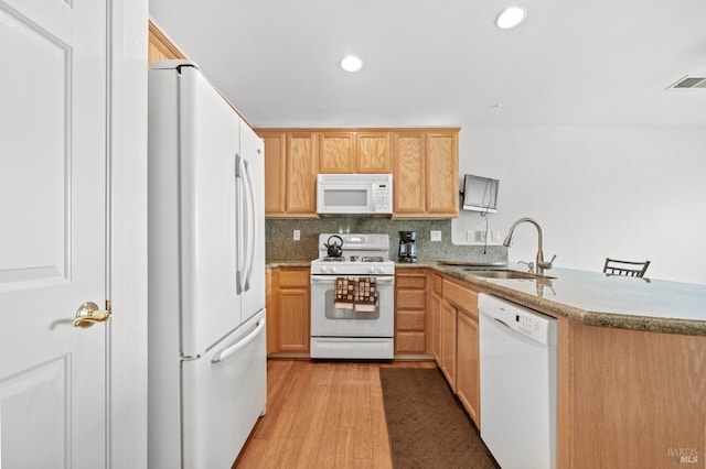 kitchen featuring white appliances, visible vents, a peninsula, light wood-style floors, and a sink