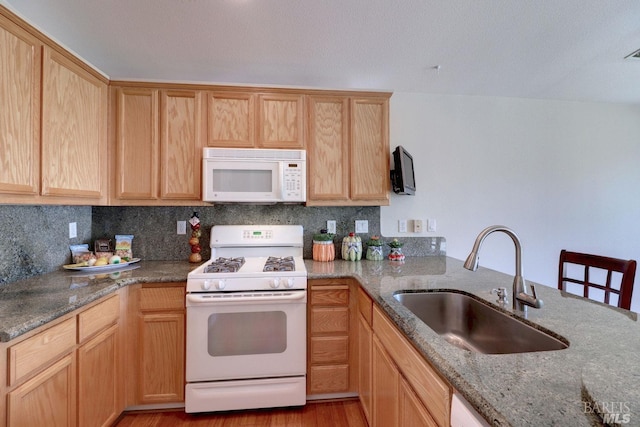 kitchen with stone counters, white appliances, a sink, light wood-type flooring, and backsplash