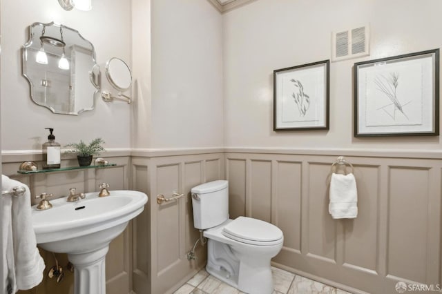 2401 Jackson St Unit 3, San Francisco, CA 94115 - half bathroom with a decorative wall, wainscoting, toilet, marble look tiles, and a sink