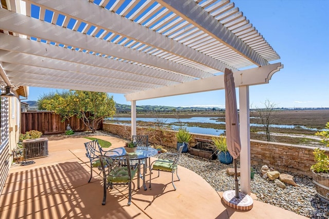 view of patio featuring fence, a pergola, outdoor dining area, and a water view