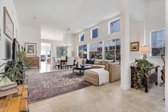 tiled living room featuring a notable chandelier, a high ceiling, and baseboards