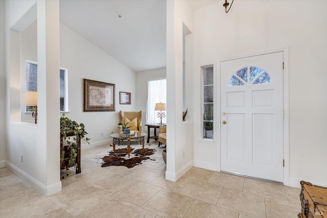 entrance foyer featuring light tile patterned floors, high vaulted ceiling, and baseboards