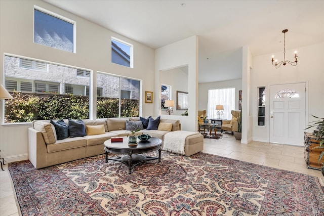 living room with an inviting chandelier, tile patterned floors, baseboards, and a towering ceiling