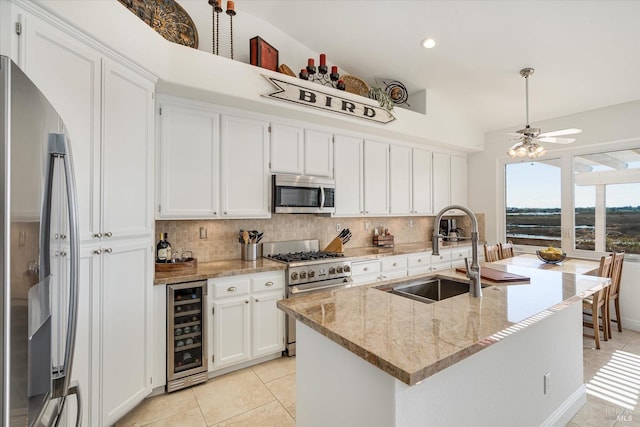 kitchen with beverage cooler, decorative backsplash, white cabinets, stainless steel appliances, and a sink