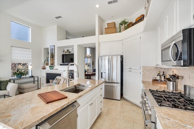 kitchen with a sink, stainless steel appliances, open floor plan, and white cabinets