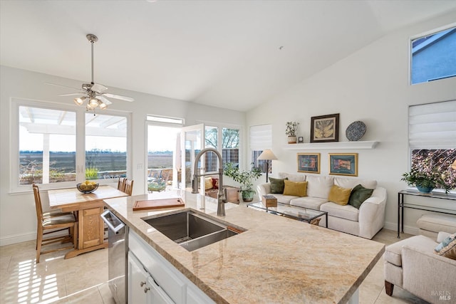 kitchen with open floor plan, a center island with sink, light stone counters, white cabinets, and a sink