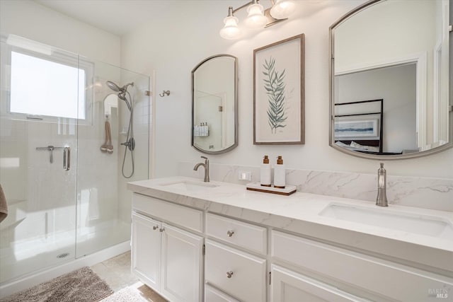 full bath featuring double vanity, a stall shower, and a sink