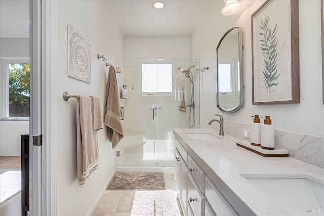 bathroom with double vanity, a healthy amount of sunlight, a stall shower, and a sink