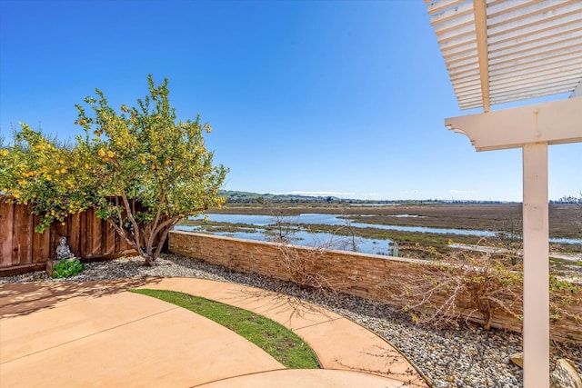 view of patio with a water view and fence