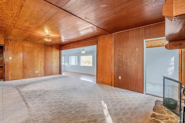unfurnished living room with wooden ceiling, wooden walls, ceiling fan, and carpet flooring