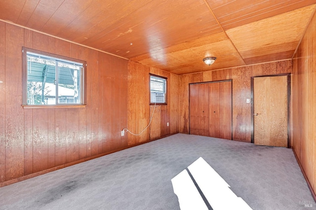 unfurnished bedroom featuring wood ceiling, wooden walls, carpet, and multiple closets