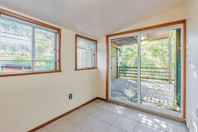 interior space featuring light tile patterned floors, baseboards, and vaulted ceiling
