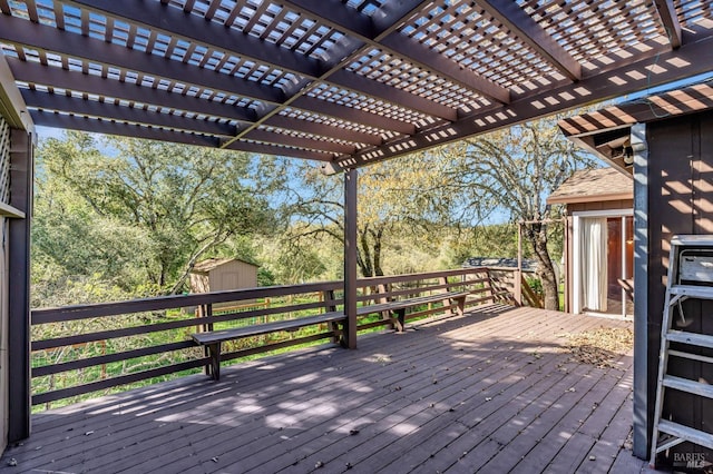 wooden terrace featuring a storage unit, a pergola, and an outdoor structure
