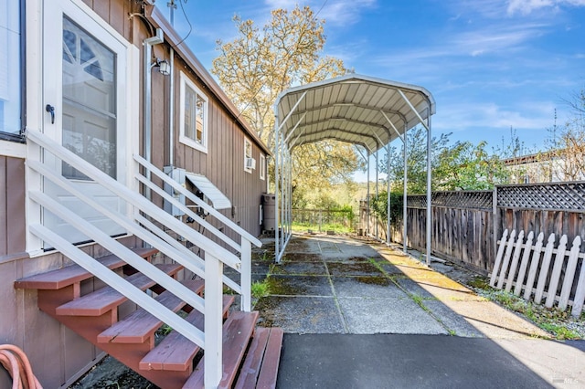 exterior space featuring a carport, stairway, driveway, and fence