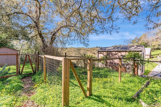view of gate featuring a shed, fence, and an outdoor structure