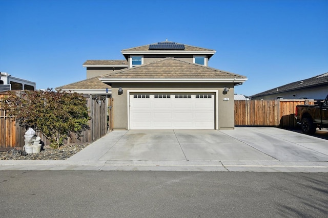 view of front of property with stucco siding, a garage, solar panels, and fence