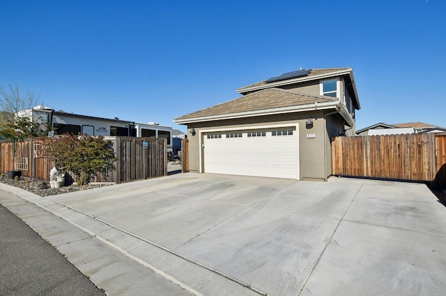 view of property exterior with stucco siding, solar panels, concrete driveway, and fence