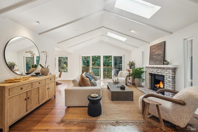 living area with vaulted ceiling with skylight, a fireplace, and wood finished floors