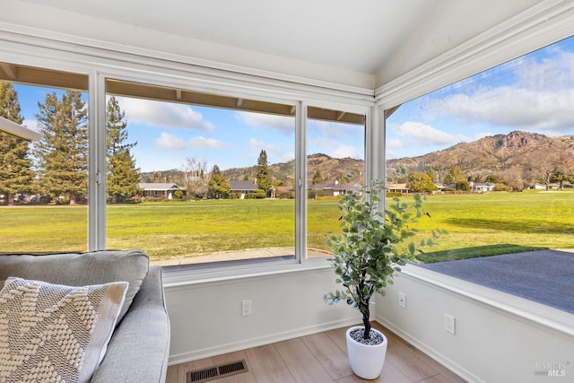 unfurnished sunroom with vaulted ceiling, visible vents, and a mountain view