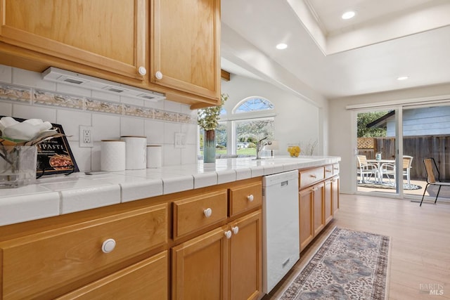 kitchen featuring tasteful backsplash, dishwasher, light wood-style flooring, a sink, and recessed lighting