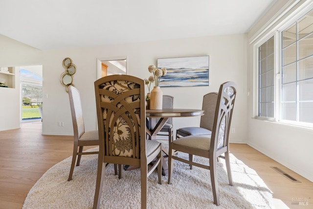 dining area featuring light wood-style flooring, visible vents, and baseboards