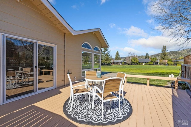 deck featuring outdoor dining area and a lawn