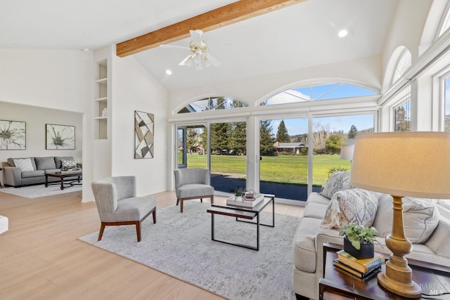 living room with a wealth of natural light, beam ceiling, high vaulted ceiling, and wood finished floors