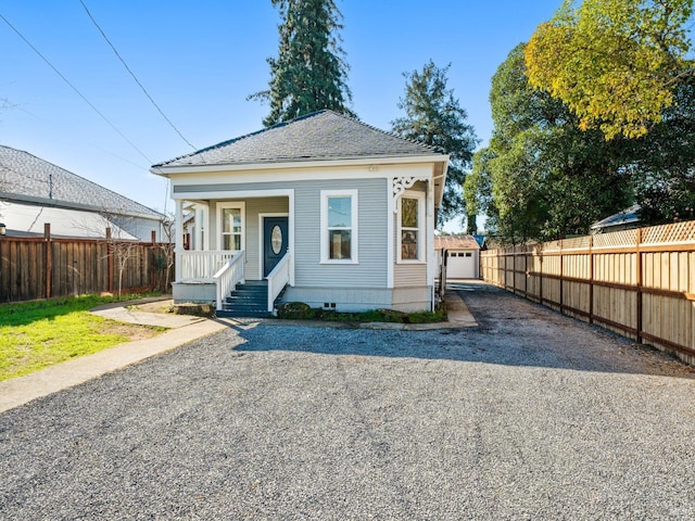 view of front of house featuring a porch, an outbuilding, fence, and driveway