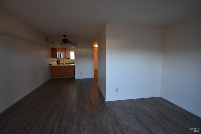 unfurnished living room with dark wood-type flooring, baseboards, and a ceiling fan