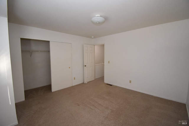 unfurnished bedroom featuring a closet and light colored carpet