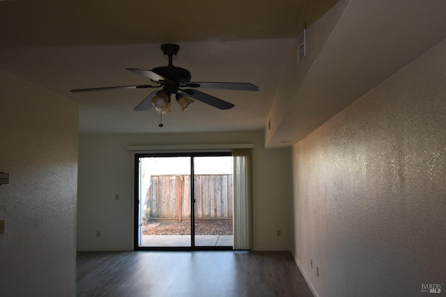 empty room with a ceiling fan, baseboards, wood finished floors, and a textured wall