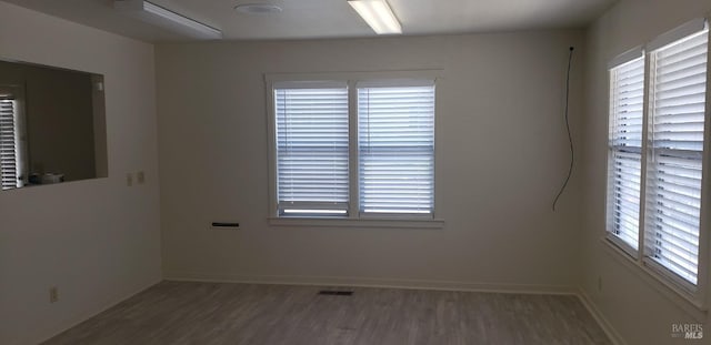 unfurnished room with visible vents, baseboards, and wood finished floors