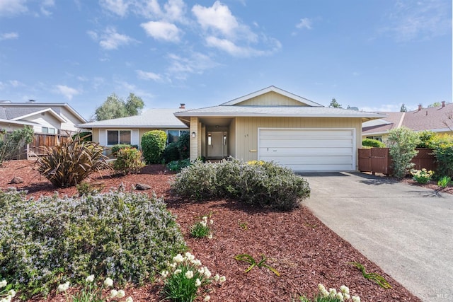 ranch-style home featuring concrete driveway, an attached garage, and fence