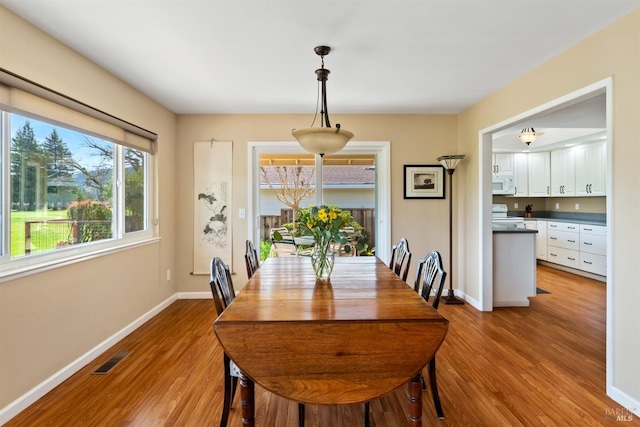 dining space with visible vents, baseboards, and wood finished floors