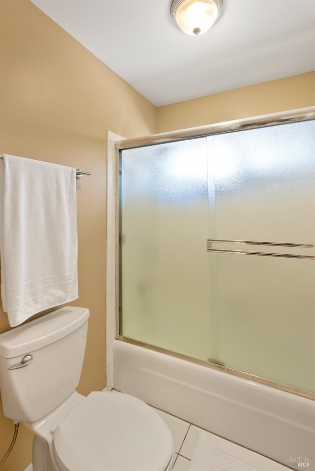 full bath featuring toilet and bath / shower combo with glass door