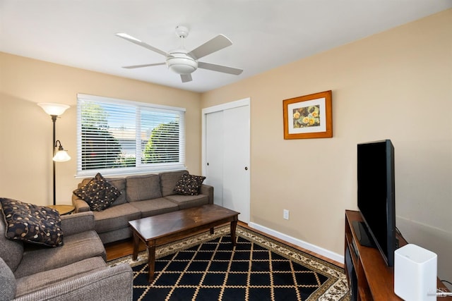 living room featuring baseboards, a ceiling fan, and wood finished floors