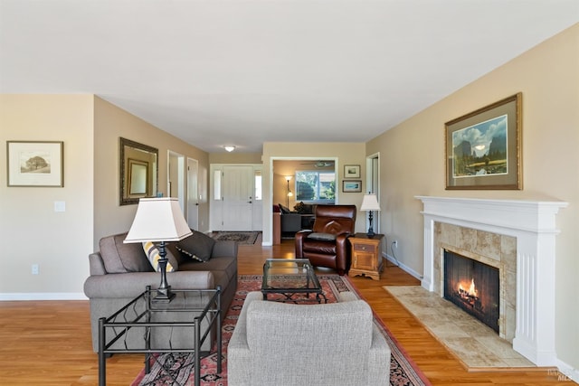 living area featuring a premium fireplace, baseboards, and wood finished floors