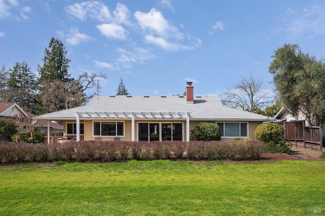 rear view of house with fence, a lawn, a pergola, and a chimney