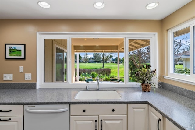 kitchen with a sink, recessed lighting, white cabinets, and white dishwasher