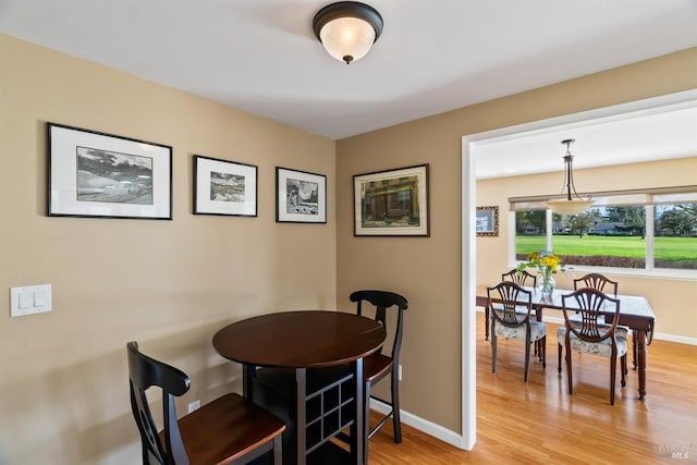 dining space with baseboards and light wood-type flooring