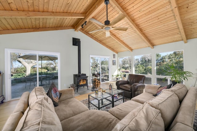 living area with beamed ceiling, wood ceiling, wood finished floors, and a wood stove