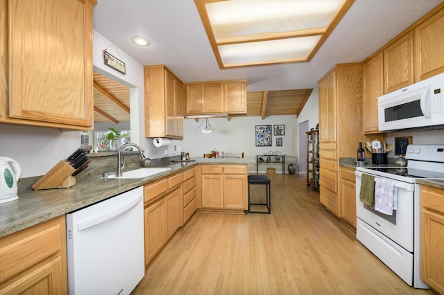 kitchen with white appliances, a peninsula, light wood-style flooring, light brown cabinetry, and a sink