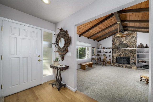 carpeted foyer entrance featuring wood finished floors, baseboards, vaulted ceiling with beams, a fireplace, and wood ceiling