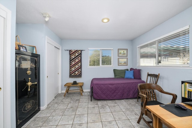 bedroom featuring baseboards, multiple windows, a closet, and light tile patterned flooring