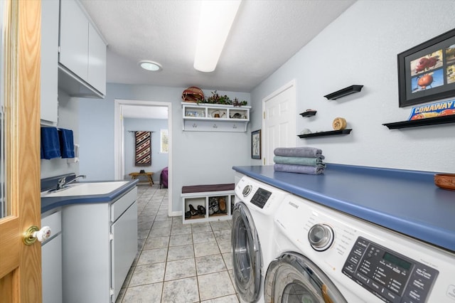 clothes washing area featuring light tile patterned floors, cabinet space, a textured ceiling, independent washer and dryer, and a sink