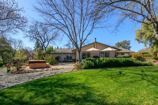 back of property with a hot tub and a yard