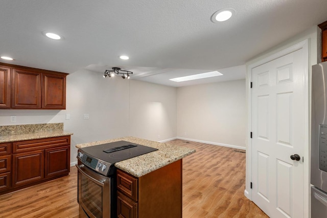 kitchen with appliances with stainless steel finishes, light stone counters, recessed lighting, and light wood finished floors