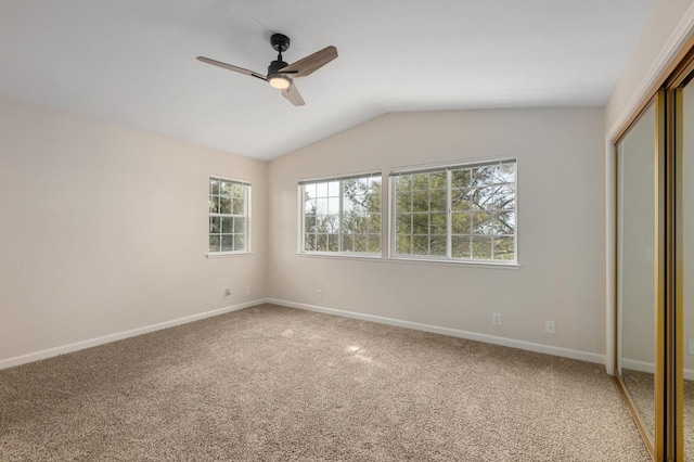 unfurnished bedroom featuring a closet, baseboards, a ceiling fan, vaulted ceiling, and light colored carpet