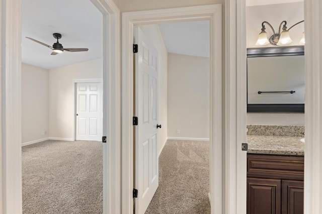 corridor featuring baseboards, carpet flooring, and lofted ceiling
