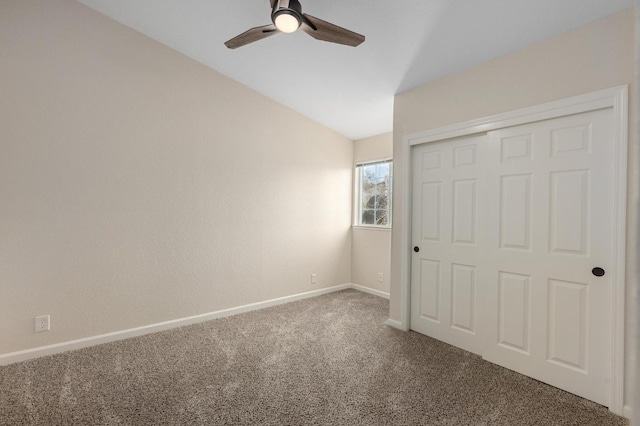 unfurnished bedroom featuring lofted ceiling, a closet, baseboards, carpet flooring, and ceiling fan